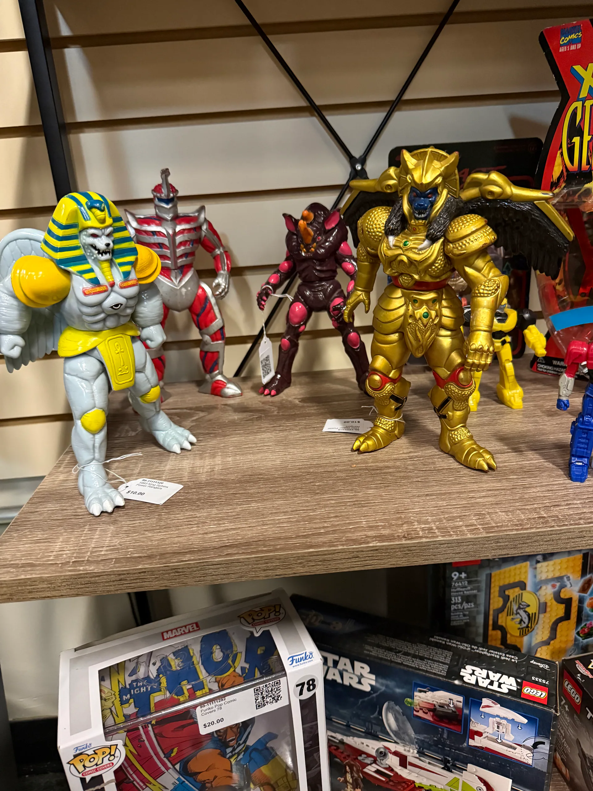 Colorful Masters of the Universe figures displayed on a wooden shelf