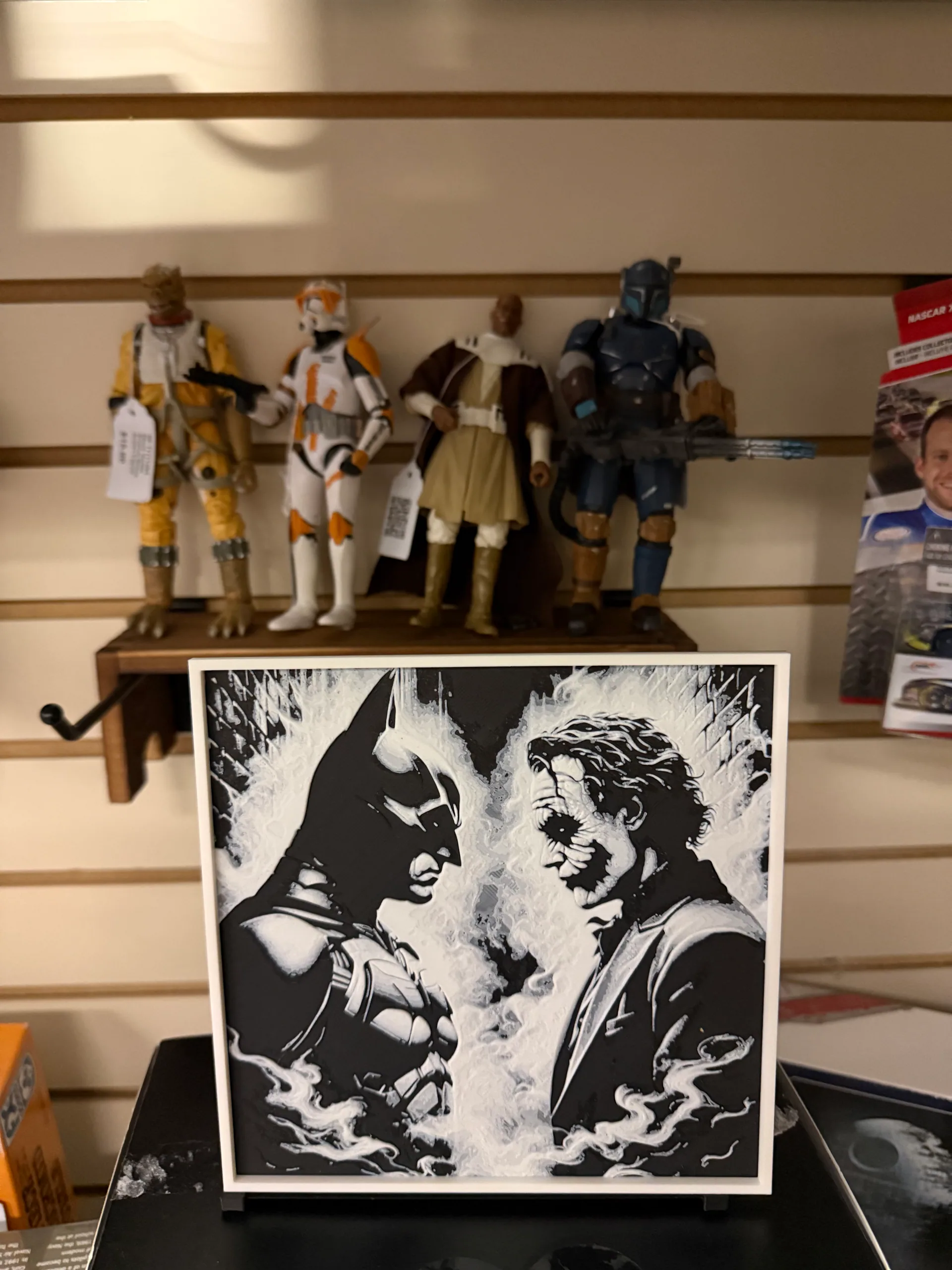 Batman and Joker artwork displayed beneath a shelf of action figures