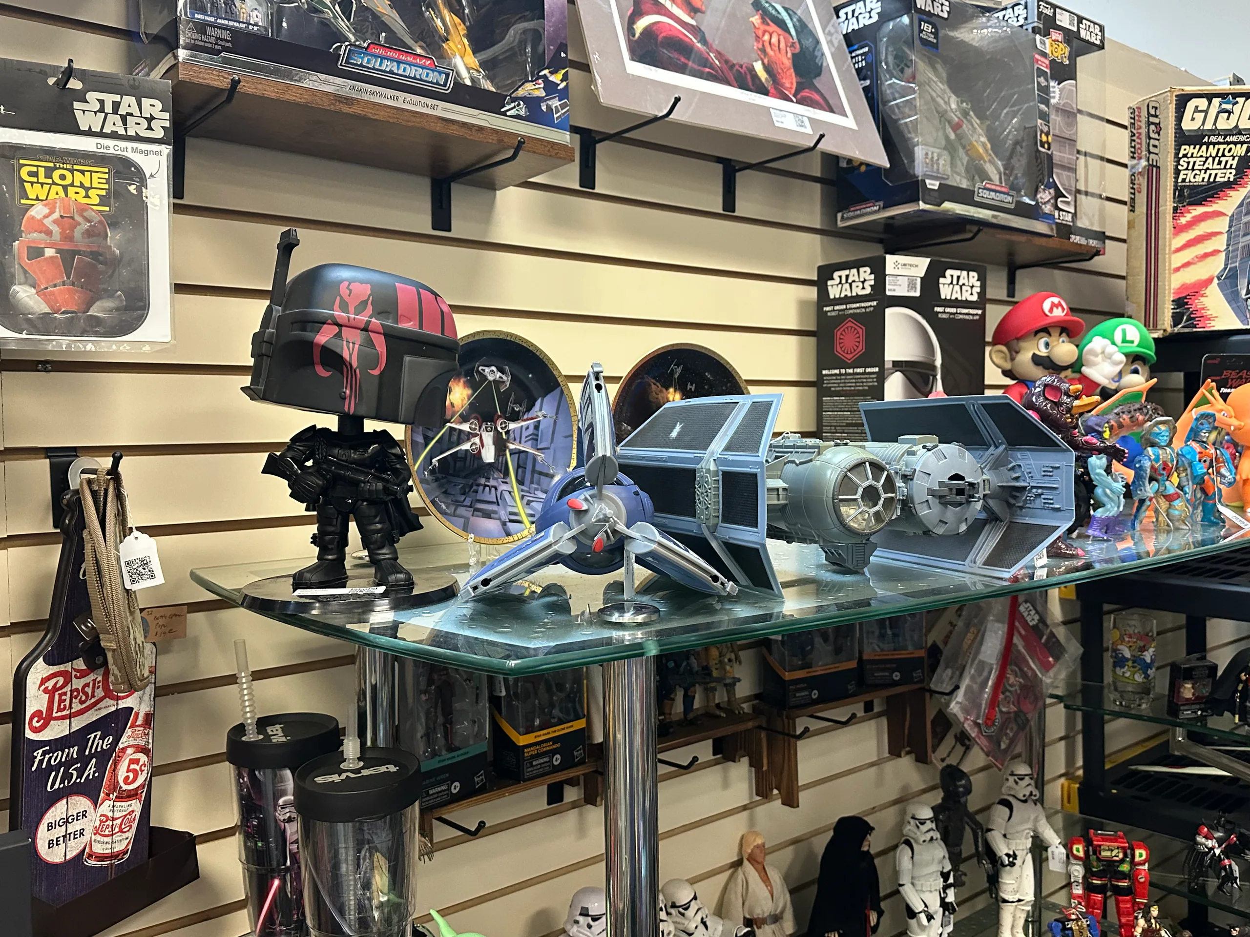 Star Wars vehicles and character figures displayed on a glass shelf